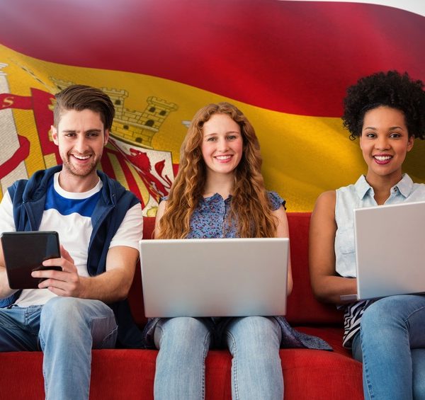 Students studying with laptops in front of Spanish flag