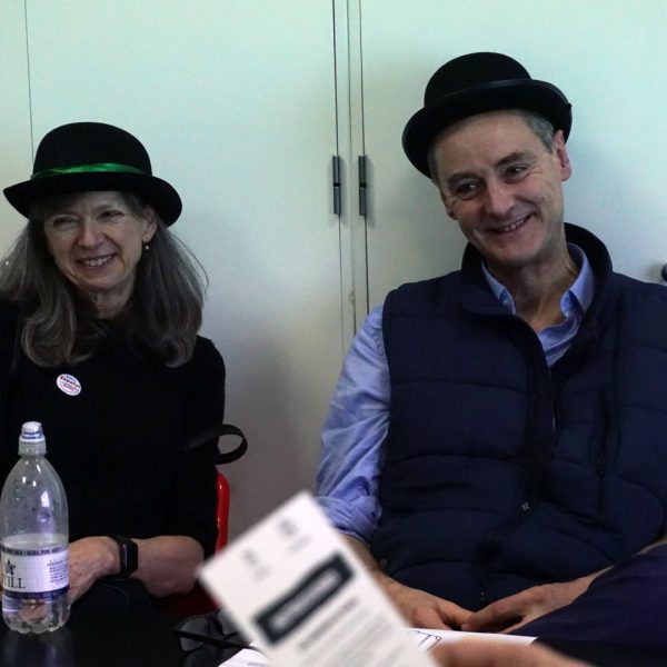 Two people wearing hats sitting at a table, smiling.