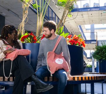 Two people sitting and talking in a modern indoor garden area.
