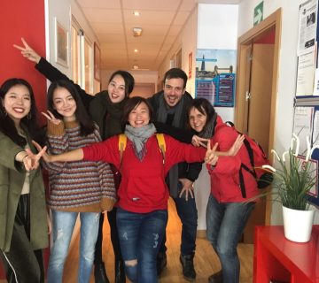 Group of six people smiling and posing in a hallway 