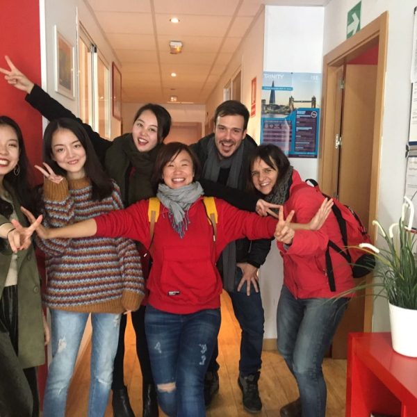 Group of six people smiling and posing in a hallway.