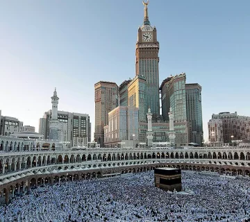Kaaba surrounded by pilgrims in Mecca with Abraj Al Bait Towers in the background.