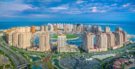 Panoramic view of a modern coastal city with skyscrapers and marina.