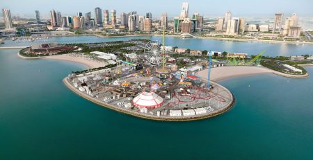 Aerial view of an amusement park on an island with a city skyline in the background.