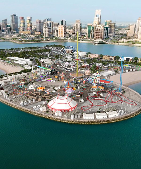 Aerial view of an amusement park on an island with a city skyline in the background.