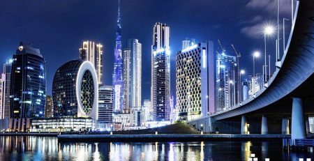 Dubai skyline at night with illuminated skyscrapers and bridge.