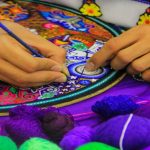 Artisan crafting colorful embroidery in Dubai handicraft center.