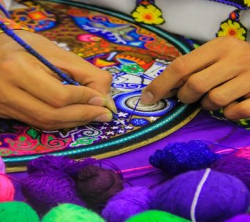 Artisan crafting colorful embroidery in Dubai handicraft center.