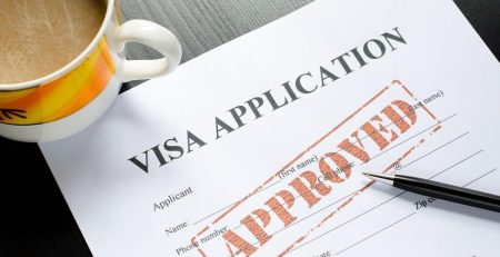 Visa application form with approved stamp and pen.
