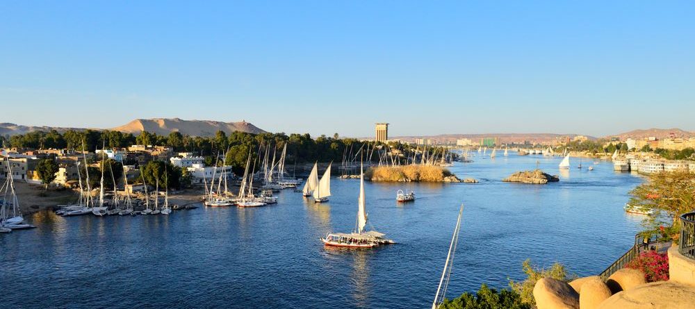 Scenic view of the Nile River in Aswan with sailboats and clear blue sky.