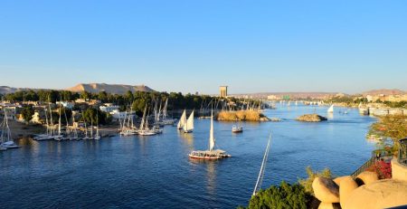 Scenic view of the Nile River in Aswan with sailboats and clear blue sky.